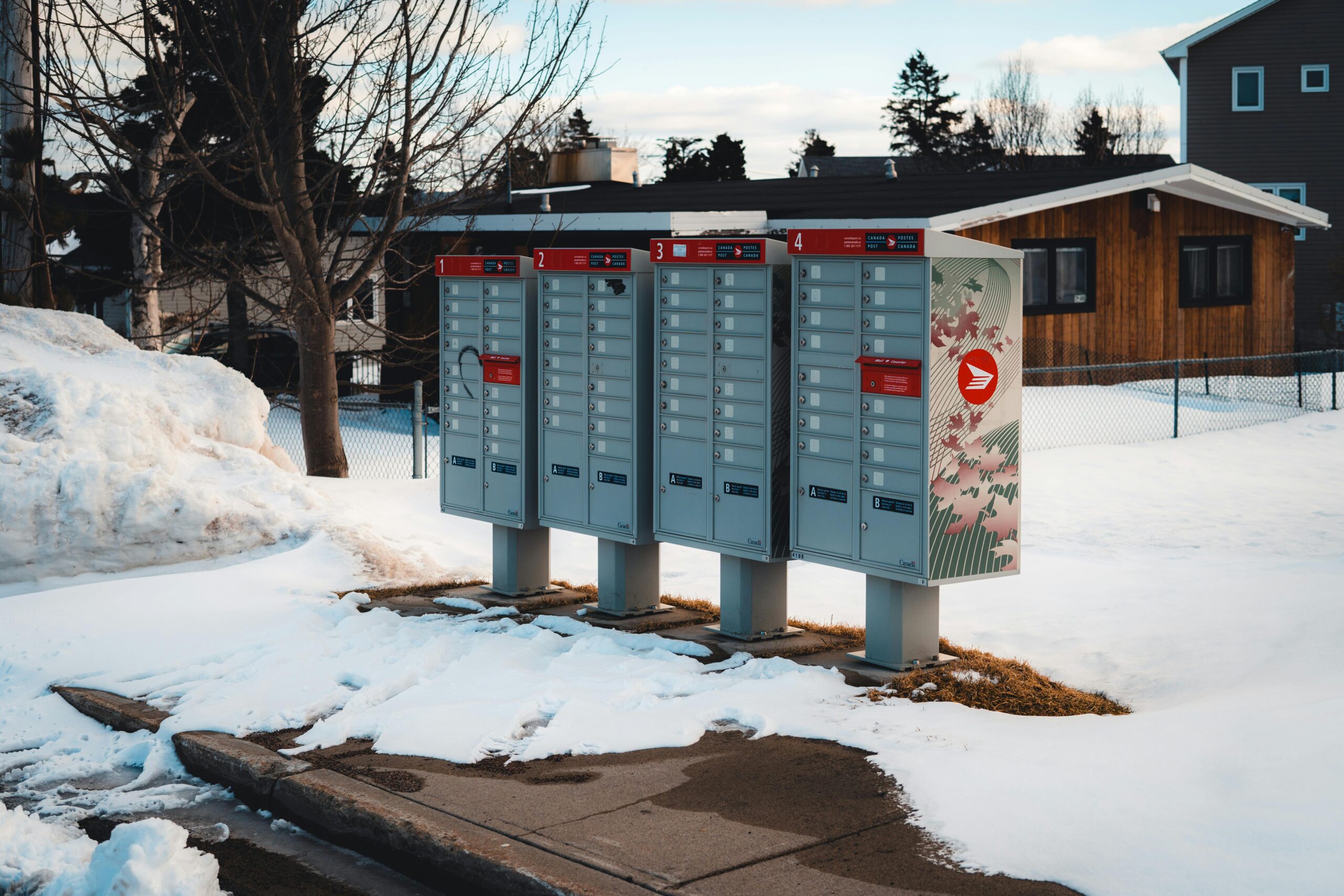 Community mailboxes in a snow-covered suburban neighborhood during winter season.